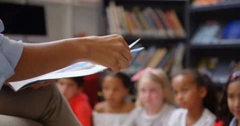 Mid section of female teacher teaching schoolkids in the school library 4k Stock Footage 106886918