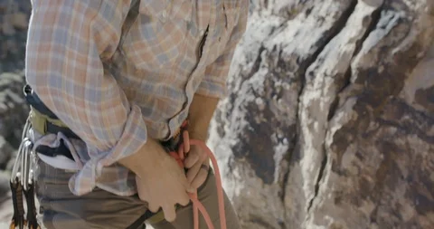 Mid section of hiker tying rope to the harness on the mountain top Stock Footage 145281385