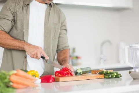 Mid section of a man chopping vegetables in kitchen Stock Photos