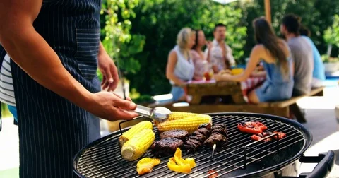 Mid section of man grilling corn, meat and vegetable on barbecue Video stock 76245573