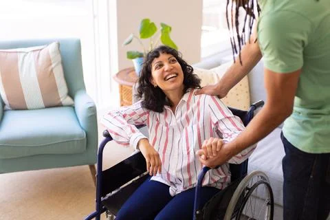 Mid section of a man holding hands of his disabled wife on wheelchair at home 스톡 사진