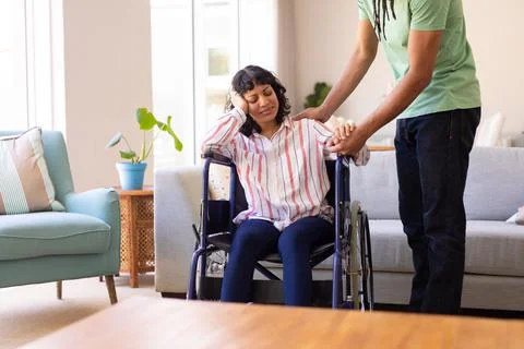 Mid section of a man holding hands of his stressed disabled wife on wheelchair 스톡 사진