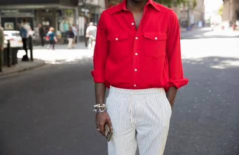 Mid section of man in red shirt and light striped trousers Stock Photos