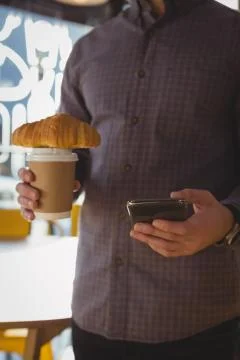 Mid section of man using phone while having coffee 스톡 사진