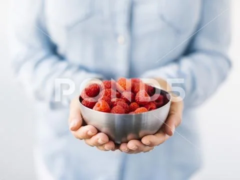 Mid Section Of Mature Woman Holding Bowl With Raspberries