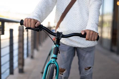 Mid section of mixed race male wheeling bicycle in the street Stock Photos
