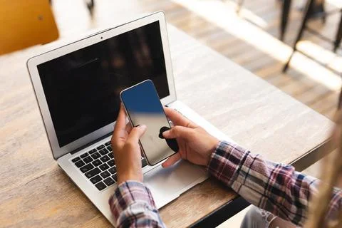 Mid section of mixed race man sitting at table outside cafe with laptop using Fotos Stock