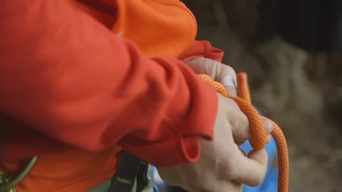 Mid-section of mountaineer tying rope around waist Stock Footage 89971778