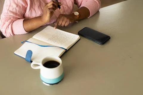 Mid section of plus size african american woman taking notes in notebook at Stock Photos