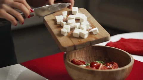 Mid-section shot of hands of unrecognizable female putting cubes of feta cheese Stock Footage 99471862