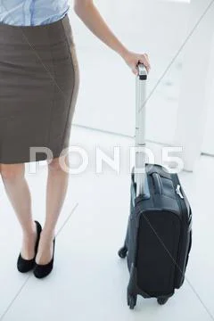 Mid section on slender classy businesswoman holding a suitcase Stock Photos