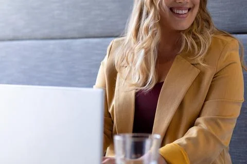 Mid section of smiling plus size caucasian casual businesswoman using laptop at Stock Photos