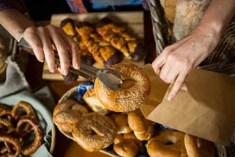 Mid section of staff packing doughnut in paper bag at counter Stock Photos
