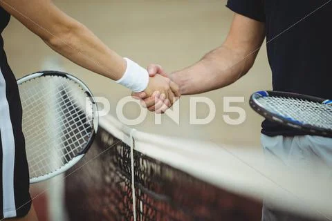 Mid Section Of Tennis Players Shaking Hands In The Court