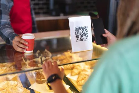 Mid section of two mixed race male taking picture of qr code and passing coffee Fotos Stock