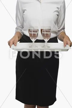 Mid section view of an air hostess carrying a tray of wine glasses Stock Photos