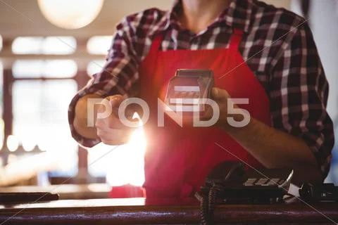Mid Section Of Waiter Showing Credit Card Machine At CafÃ©