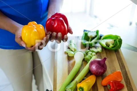 Mid-Section Of Woman Holding Red And Yellow Bell Pepper