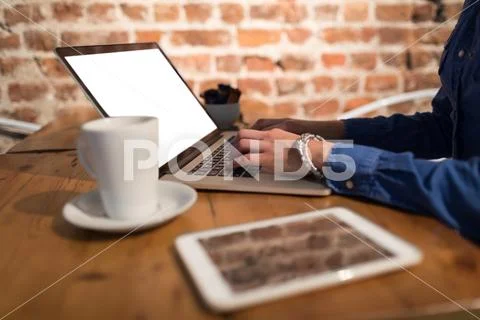 Mid Section Of Woman Using Laptop In Cafe