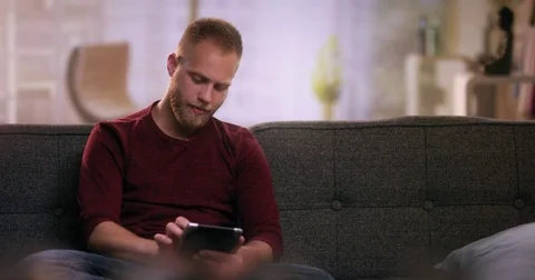 Mid Shot of attractive young boy sitting on sofa using tablet Stock Footage 77191285