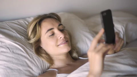 Mid-shot elevated view of adult woman using smart phone while lying in bed after Stock Footage 277967249