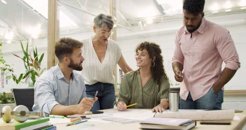 Mid-shot front view of cheerful group of coworkers going over details of new Stock Footage 277949647