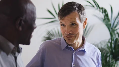 Mid-shot front view of diverse group of coworkers chatting and looking at Stock Footage 278041278