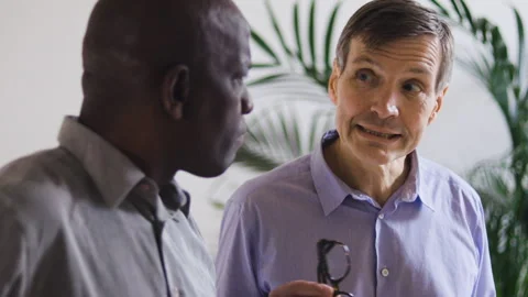 Mid-shot front view of diverse group of coworkers chatting and looking at Video stock 278041390