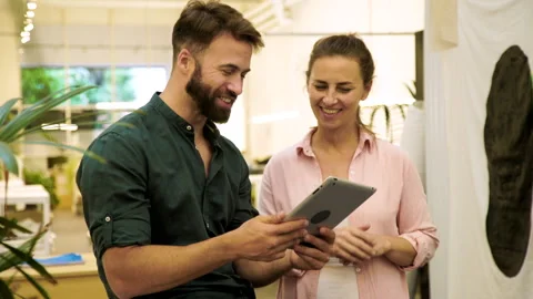 Mid-shot front view of two coworkers sharing ideas for project while looking at Stock Footage 277957051
