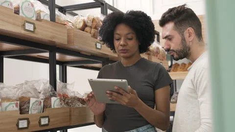 Mid-shot front view of two diverse small business owners checking their stock on Stock Footage 277958511