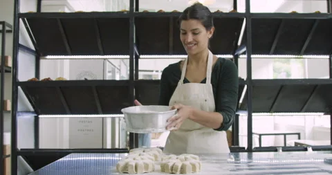 Mid-shot front view of young female pouring flour on  bread dough with flour Stock Footage 277958700