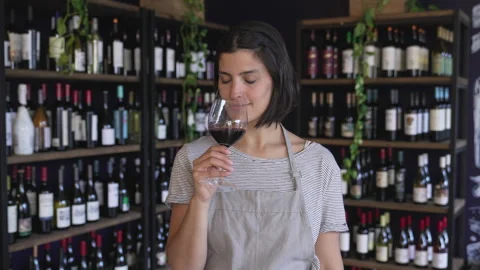 Mid-shot front view of young female wine shop owner holding glass of wine while Stock Footage 277963800