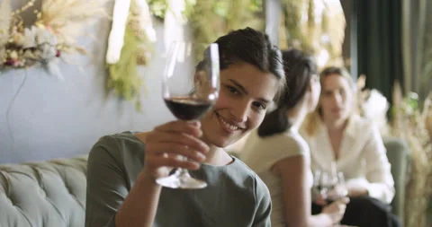 Mid-shot front view of young woman looking at camera while raising her glass of Stock Footage 277966742