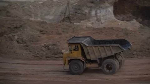 Mid shot of heavy mining trucks carring cargo in opencast mining quarry in sunny Vidéo 75377353