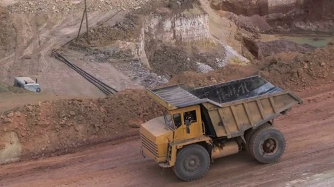 Mid shot of heavy mining trucks carring cargo in opencast mining quarry in sunny Stock Footage 75388824
