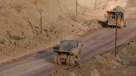 Mid shot of heavy mining trucks carring cargo in opencast mining quarry in sunny Video stock 75390028