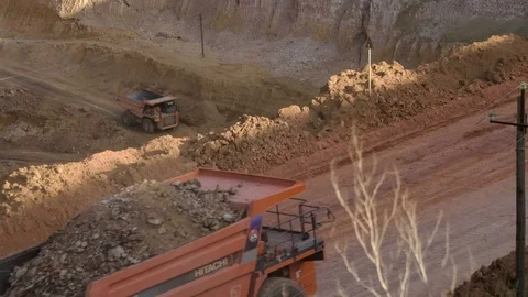 Mid shot of heavy mining trucks carring cargo in opencast mining quarry in sunny Stock Footage 75390751