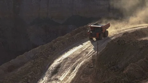 Mid shot of heavy mining trucks carring cargo in opencast mining quarry in sunny Stockbeeldmateriaal 75392123