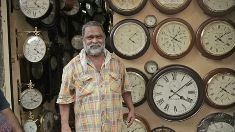 A mid shot of Indian antique wall clock shop owner standing, India Stock Footage 85761853