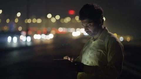Mid shot of an Indian male using mobile phone against moving city traffic Vídeo Stock 330885869