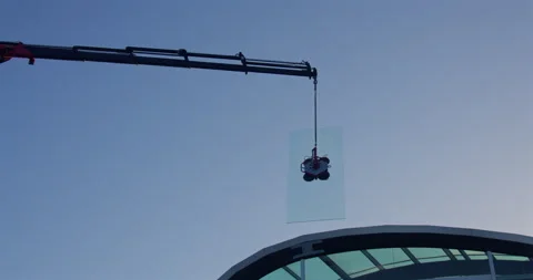 Mid Shot of a lorry crane lifting And swinging a pane of glass onto a hotel Vídeo Stock 336724501