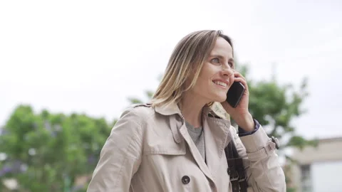 Mid-shot low angle view of adult woman answering phone call while walking in the Stock Footage 277967018