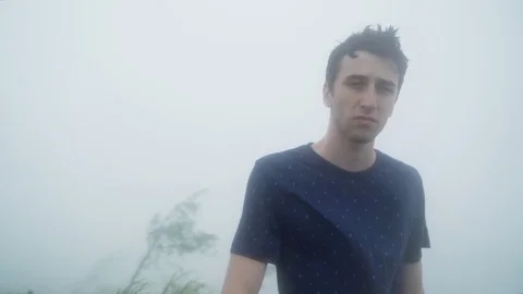 Mid shot of a man up a mountain in a monsoon storm on an island in the 스톡 동영상 94120445