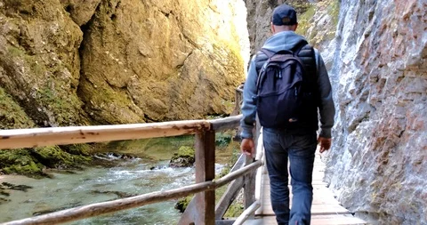 Mid shot of man walking across wooden bridge over river. Stock Footage 119333401
