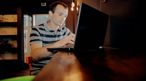 Mid shot Man working on computer and drink coffee in cafe Stock Footage 65717337