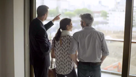 Mid-shot rear view of real estate agent giving information about property's Stockbeeldmateriaal 277973177