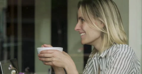 Mid-shot side view of female digital nomad worker drinking tea while working Stock Footage 277965277