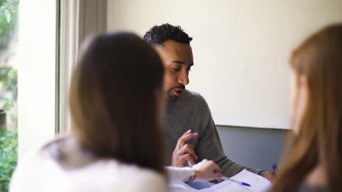 Mid-shot side view of relaxed group of coworkers going over details of marketing Stock Footage 278025425