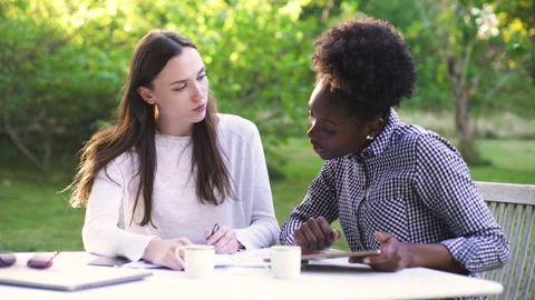 Mid-shot side view of relaxed group of coworkers going over details of marketing Stock Footage 278025454