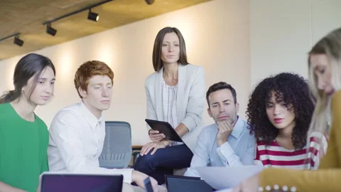 Mid-shot side view of relaxed group of coworkers going over details of marketing Stock Footage 278027613